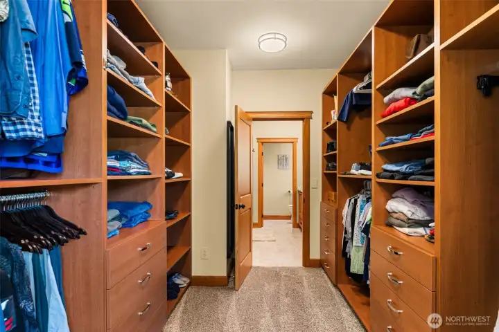 Expansive walk-in closet thoughtfully designed with custom built-in cabinetry, extensive shelving, hanging space, & integrated drawer storage to maximize organization and functionality. The well-appointed layout provides space for wardrobe & accessory storage while maintaining the home’s consistent craftsmanship and warm wood finishes throughout.