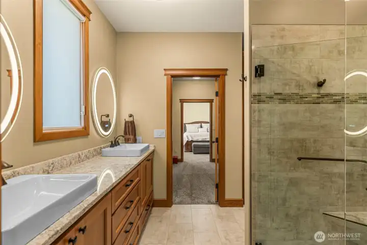 custom cabinetry, & quality finishes throughout. The oversized walk-in tile shower with frameless glass enclosure creates a spa-like atmosphere with warm wood accents and thoughtful. Seamlessly connected to the spacious primary suite and custom walk-in closet for effortless everyday living.