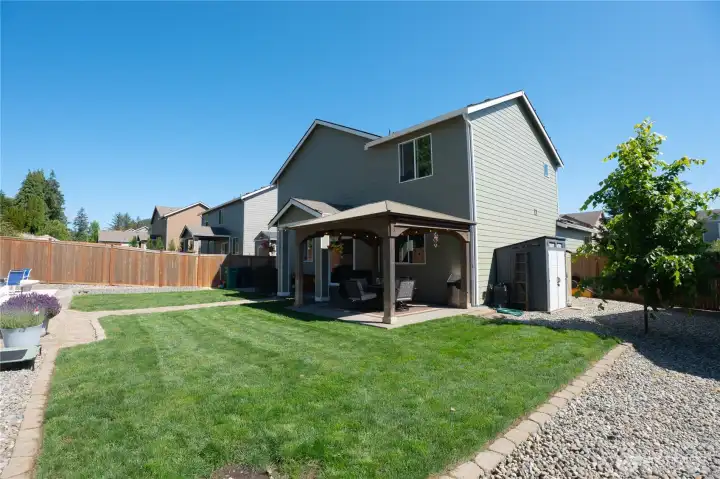 Good sized backyard with lush green grass, gazebo, garden area and pavers for a fire pit