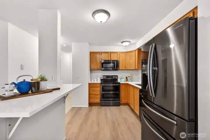 Quartz counters, a deep undermount stainless sink, and stainless appliances make this kitchen as functional as it is welcoming, with the island offering a perfect spot to gather. New LVP flooring underfoot ties the space together with a clean, durable finish.