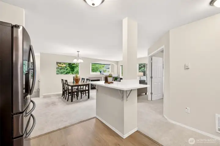 The island doubles as a natural divide between the kitchen and the open dining and living areas, keeping the floor plan airy and connected. New LVP and carpet flow throughout, while a hallway leads off to the home's comfortable bedroom wing.