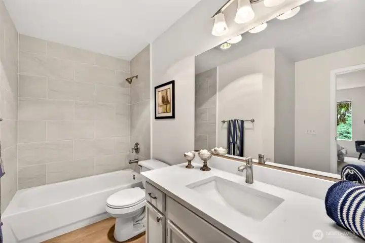 The updated primary bath continues the home's fresh, cohesive style with new tile surround, a quartz counter and undermount sink, and modern fixtures. Bright lighting and a roomy vanity make daily routines feel effortless.