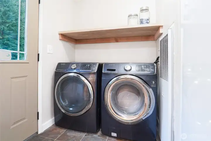 Separate laundry area featuring front-load appliances, utility shelving, and additional storage potential. Separate laundry area featuring front-load appliances, utility shelving, and additional storage potential.