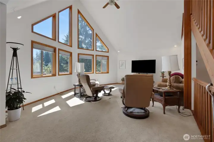 Living room with vaulted ceilings and massive windows flooding the area with natural light. Living room with vaulted ceilings and massive windows flooding the area with natural light.
