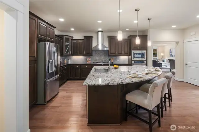 The chef's kitchen is a dream, featuring a generous island, gas cooktop with hood, and double Oven!