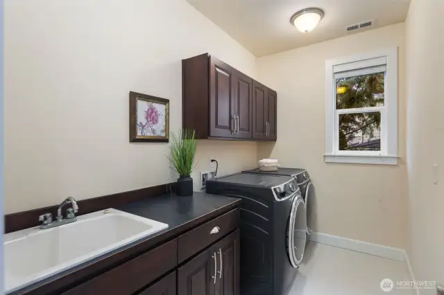 Upper level laundry room with side-by-side washer and dryer, utility sink and plenty of storage.