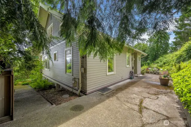 The backyard entrance leads to the patio area to the backdoor off the kitchen. To the left just out of site, sits a rustic garden shed, wood storage and the walkway around to the front of the house and porch.