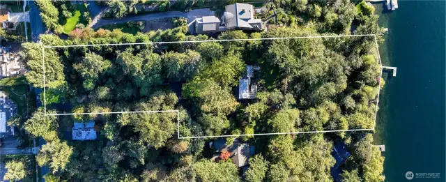 An aerial perspective reveals the expansive scope and natural privacy of Evergreen Lakeshore Preserve. Spanning over 1.5 acres with 147 feet of private Lake Washington shoreline, this rare estate property is richly forested and gently slopes toward the water’s edge. Framed by mature trees and quiet lanes on both sides, it offers dual street access—ideal for future reimagining—while preserving the beauty, serenity, and seclusion that define this legacy property.