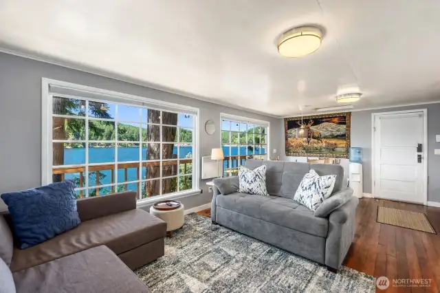 Living area with windows on three sides, original wood floors, and modern lighting.