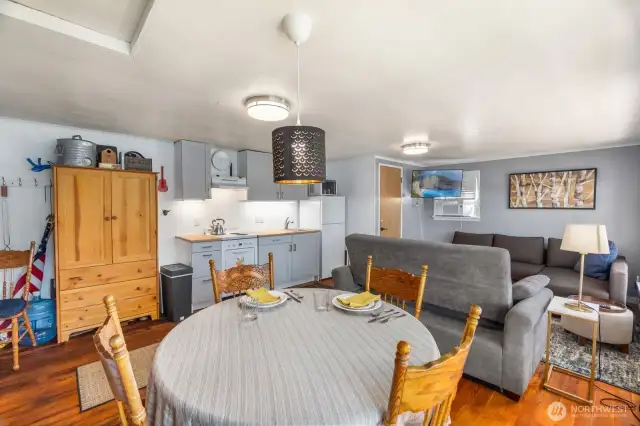 Wide view from dining room showing living, dining, and kitchen layout with wood floors.
