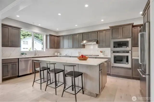 Kitchen with oversized island & stainless steel appliances. Previous built Peak house. Finishes may be different.