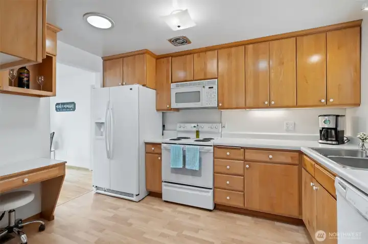Kitchen has a little desk space to the left. Clean cabinets and Laminate flooring.