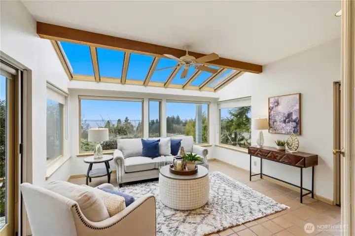 The sunroom is flooded with natural light through multiple windows, skylights, and two sets of doors - a bright, inviting space to take in the surrounding views.