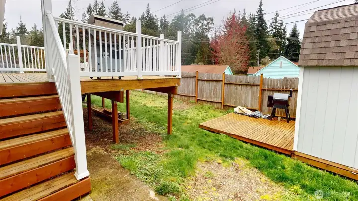 Stairs lead from either side of the deck to the fenced backyard.