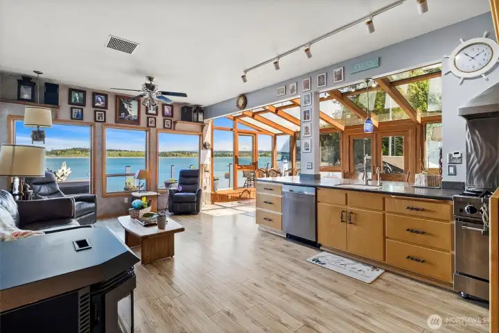 Open kitchen boasting beautiful modern stainless steel appliances, living room, and sunroom dining area all situated to take in the truly magical setting.
