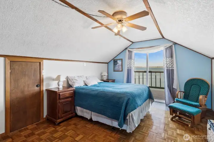Upper-level waterfront bedroom opens to a private balcony overlooking the water.