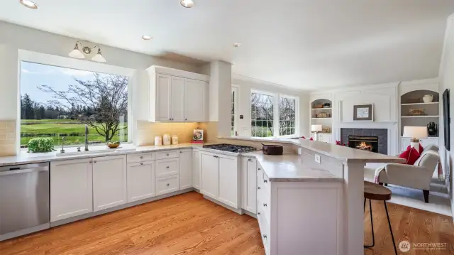 Renovated kitchen showcases exquisite cream cabinetry, raised eating bar for 4, updated lighting and tranquil views of the golf course.