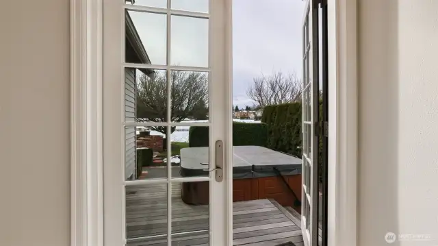 French doors from den lead to deck with secluded hot tub