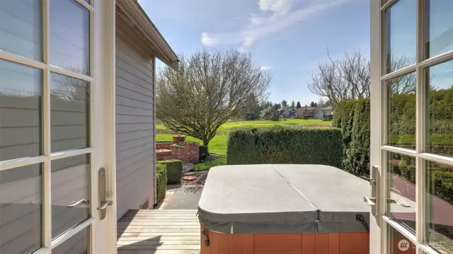 French doors from den lead to deck with secluded hot tub