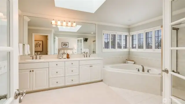 Primary bathroom features a jetted soaking tub, dual sinks, and skylight