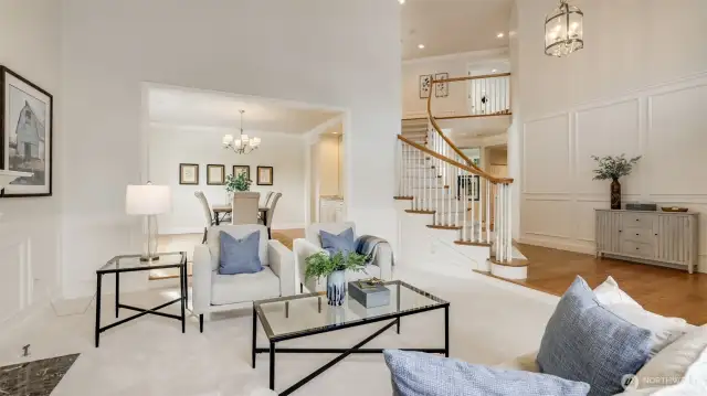 The grand foyer highlighted by a custom wainscot wall and living area lead to formal dining area