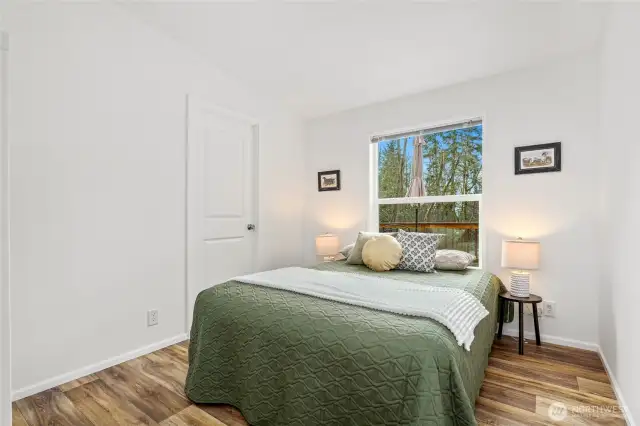 Bedroom two of three offers a beautiful view of the deck and stunning sunsets through the trees.