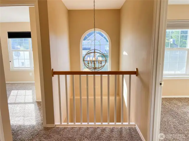 Appealing light fixture, arched window and railing overlooking the front foyer between the first & second bedrooms.