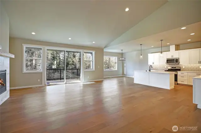 Open floor plan with a vaulted ceiling and engineered hardwood floors.