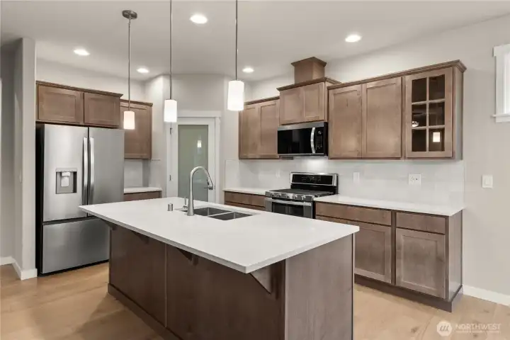 Beautiful Canyon Creek Maple cabinetry with full extension guides and soft close drawers and quartz countertops throughout the home. A walk-in pantry in the heart of the kitchen for all your kitchen needs.
