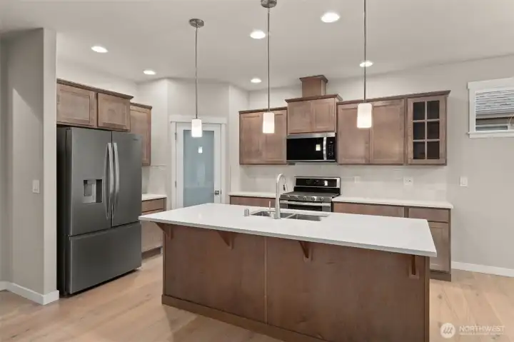 Beautiful Canyon Creek Maple cabinetry with full extension guides and soft close drawers and quartz countertops throughout the home. A walk-in pantry in the heart of the kitchen for all your kitchen needs.