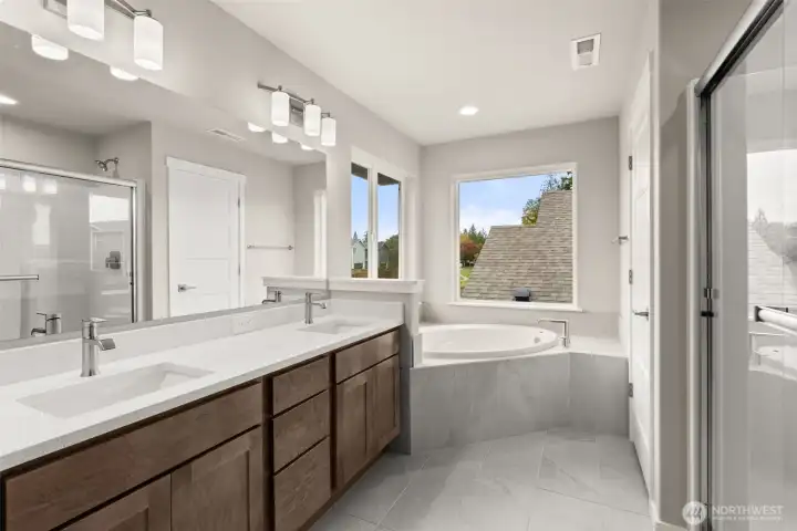 Five-piece primary bath features tile flooring with full tiled tub deck for the soaking tub, walk-in shower and dual vanity.