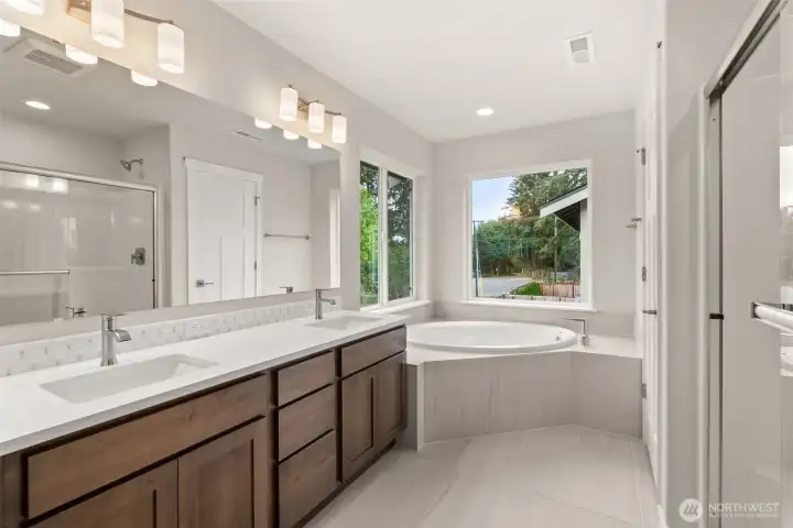 Five-piece primary bath features tile flooring with full tiled tub deck for the soaking tub, walk-in shower and dual vanity.