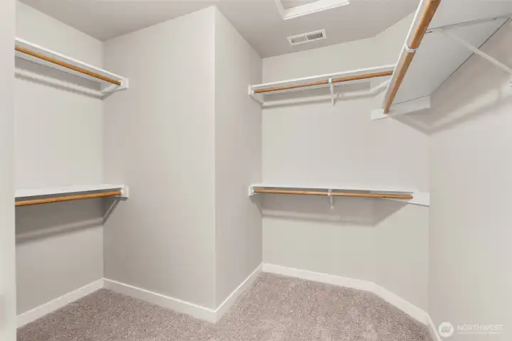 Primary closet is walk-in with extra solid storage shelves above the hanging rods.
