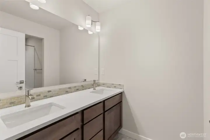 Upstairs hall bath features a dual vanity with quartz counters and backsplash.