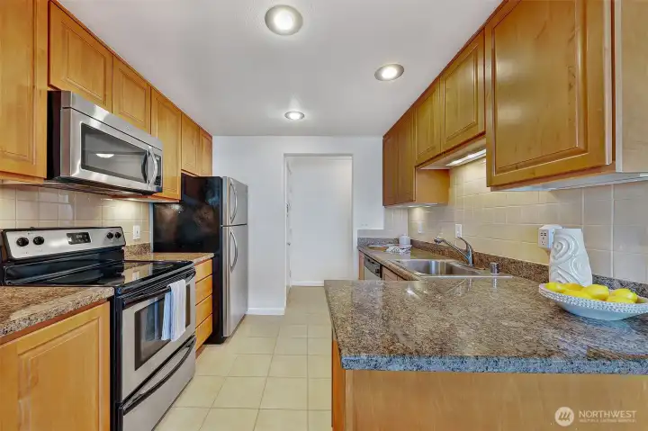 Well-appointed kitchen with granite breakfast bar, tile floors and stainless appliances.