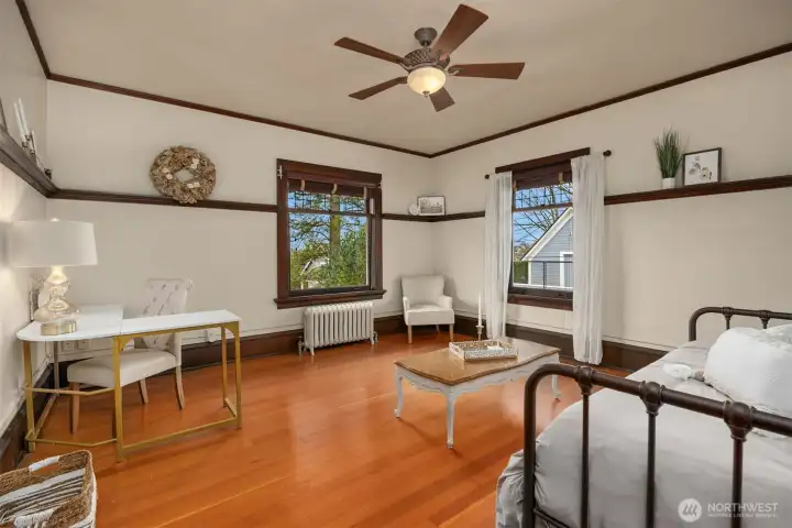 A generously sized bedroom offers flexibility for modern living, comfortably accommodating both sleeping and has a large walk-in closet with plenty of space to add a bedroom workspace. Hardwood floors, original trim, and natural light create a calm, functional room ideal for guests or everyday living.