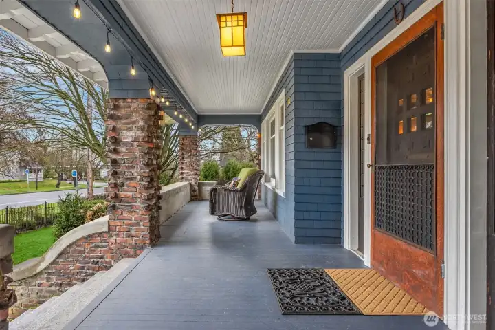 The expansive covered front porch is a defining feature — wrapped in brick columns, softly lit with café lighting, and overlooking mature landscaping. This is a place for morning coffee, evening conversations, and watching downtown Snohomish stroll by.