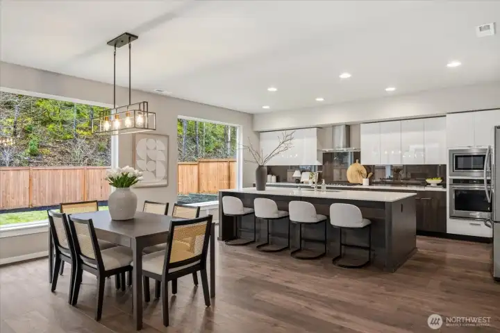 The heart of the home; featuring a spacious quartz prep island with breakfast bar seating, stainless steel appliances, and expansive windows that fill the space with natural light.