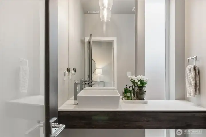 The powder bath reflects the home's cohesive design language, featuring a contemporary floating vanity and designer finishes.