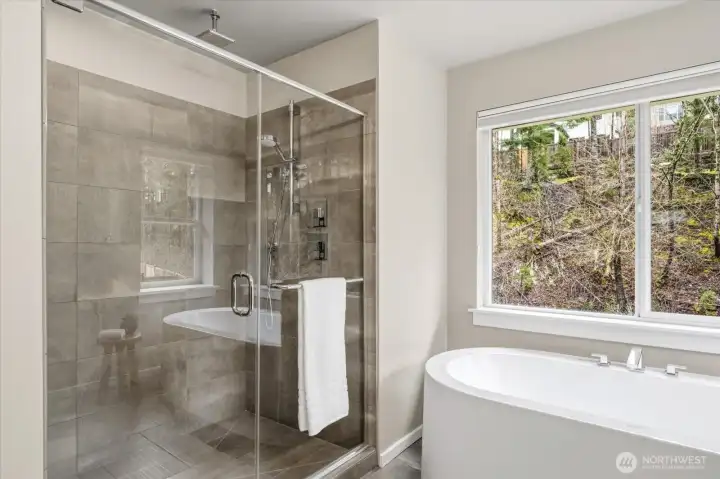 A spacious walk-in shower with clean, modern finishes and a ceiling-mounted rain feature enhances the spa-like feel.