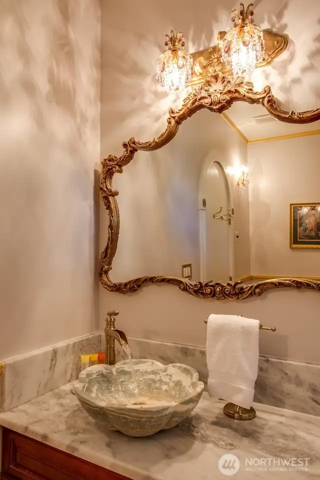 Elegant Palace Suite bathroom featuring   a stone vessel sink, marble shower with dual showerheads and crystal lighting.