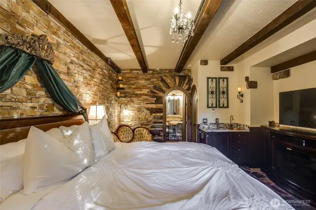 The Olde Rose Suite's luxuriously dressed King Bed adorned with silk curtains hanging from an Old World style bed crown, accented with a crystal chandelier above.