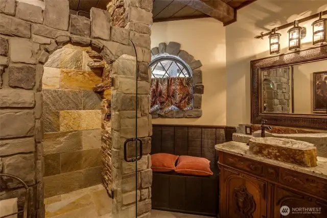 The Castle Suite amazes with its custom stone shower featuring a waterfall and rain shower head, antique vanity and rustic stone sink