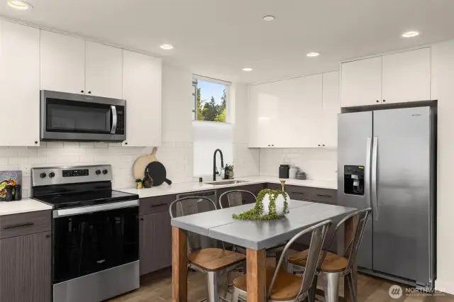 Kitchen features stainless steel appliances, window treatments and a quartz countertop.