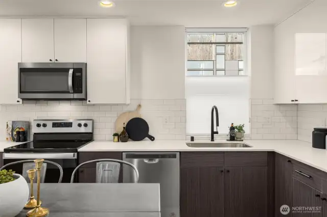 Kitchen features stainless steel appliances, window treatments and a quartz countertop.