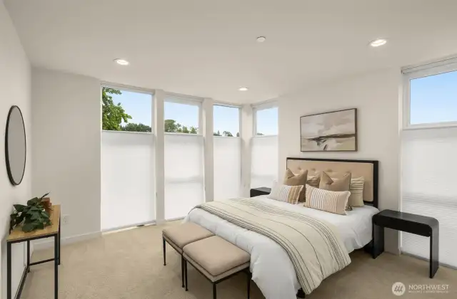 Primary bedroom features floor-to-ceiling windows, custom window treatments, carpet and an ensuite.