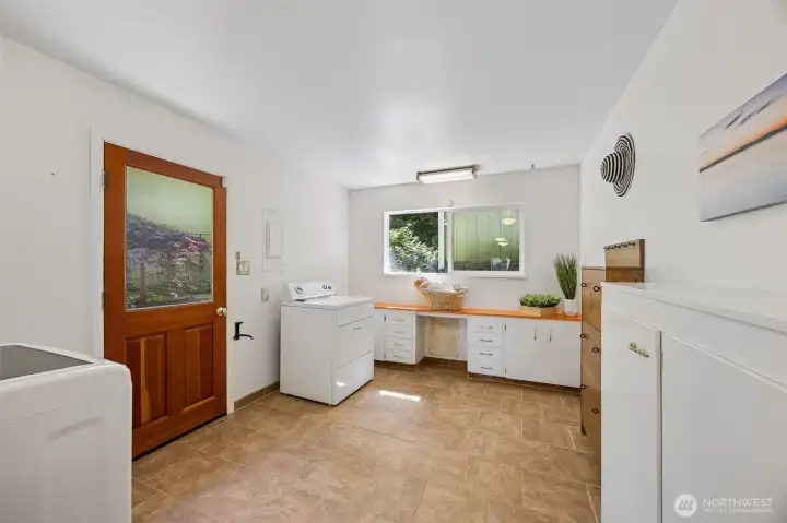 Beyond the kitchen find an extra large mud/laundry room, sewing space or garden prep area with clever shoe storage cabinets and more. This side door leads up a few short steps to the level parking area/shop and well.