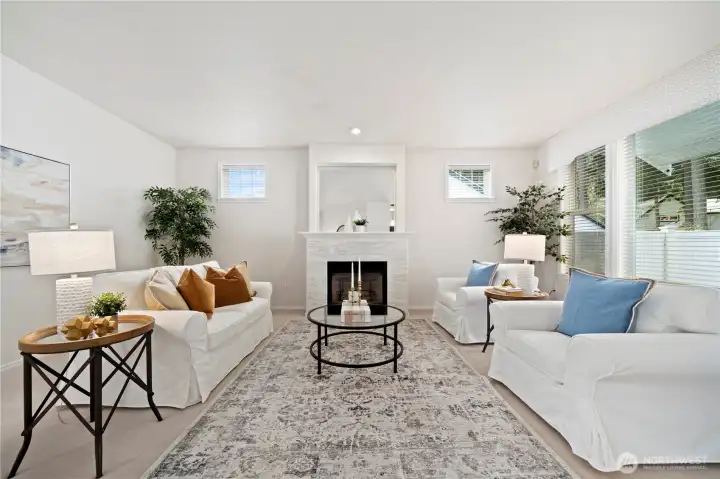 The gracious living room features a   cozy gas fireplace and expansive picture   windows that fill the space with natural light.