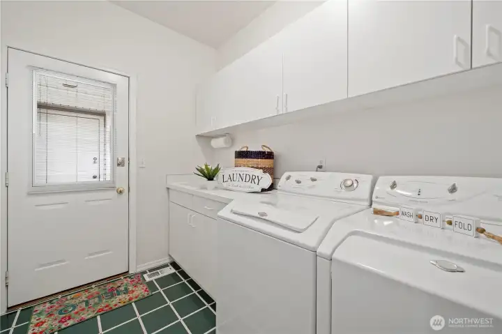 The laundry room features a utility sink, storage cabinets and a broom closet. Breezeway access to the two-car garage is just through that door.