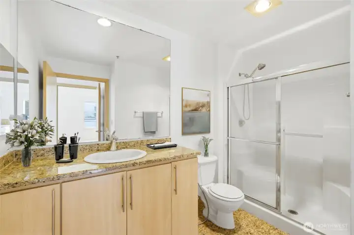 The primary bathroom offers a modern, spa-like experience with granite countertops and a sleek walk-in shower. It’s designed to feel open and bright, making your morning routine more enjoyable.